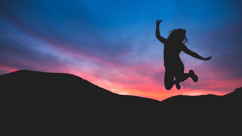 A woman jumping is pictured in front of a sunset, all that is seen is a silhouette. 