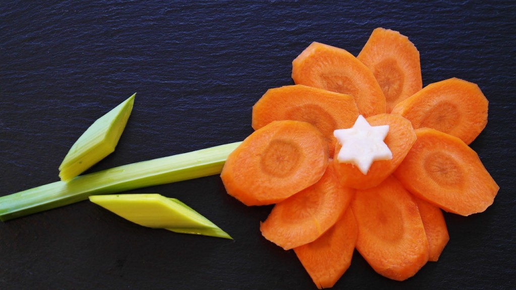 A flower made out of veggies and cheese, the flower is made of carrots and the rest is green veggies. 