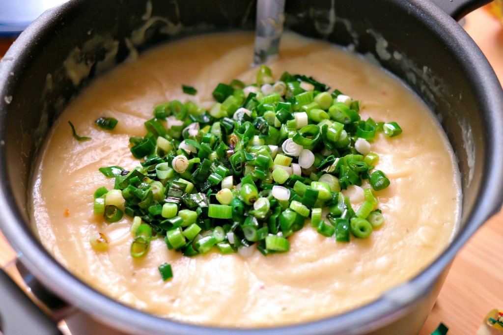 Queso with green onions mixed in a bowl.