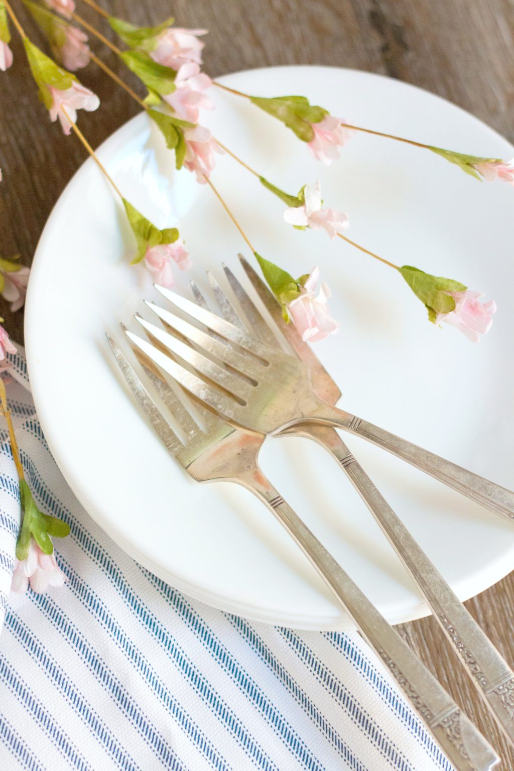 A plate is adorned with vintage forks and small pink flowers. 