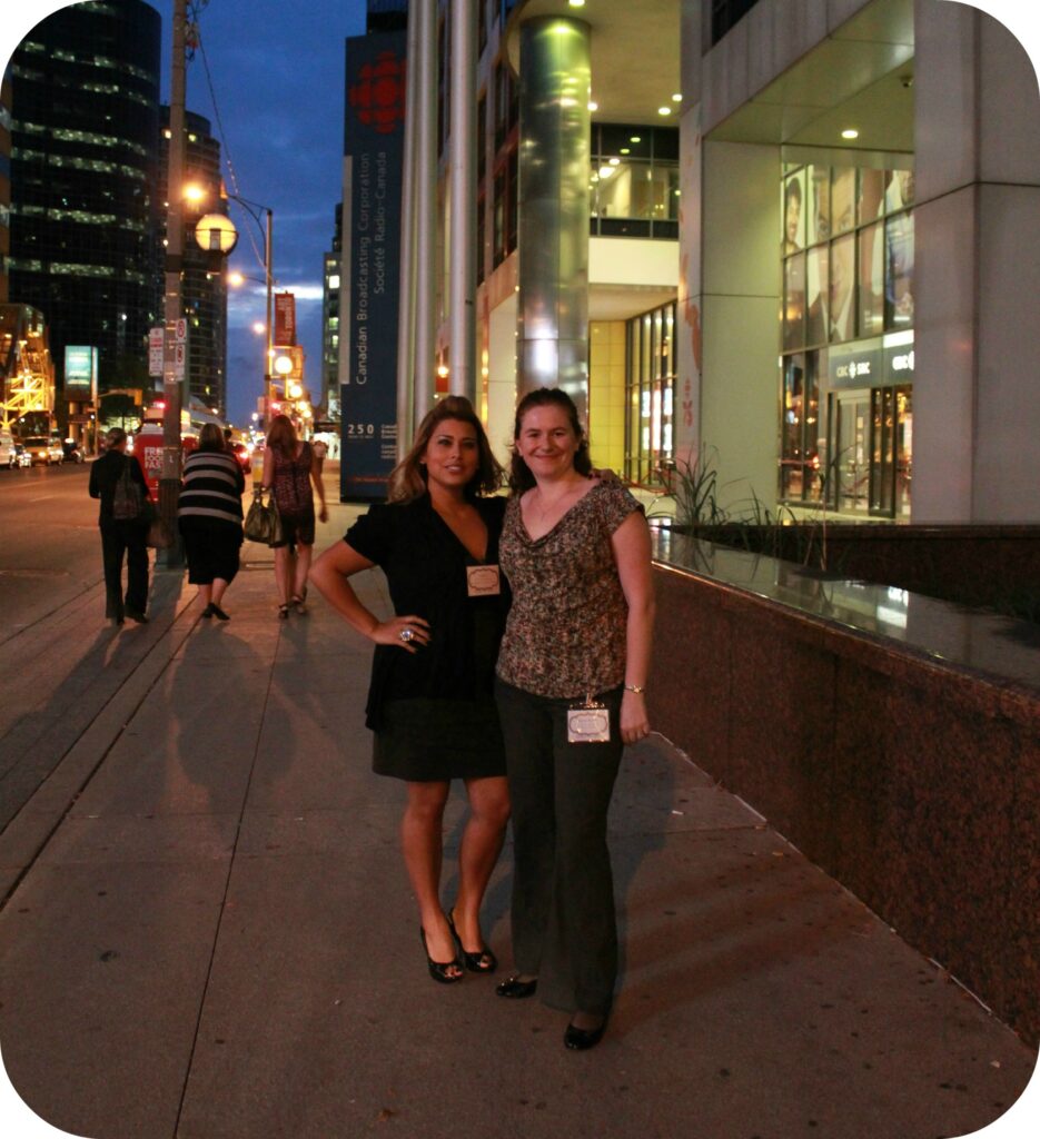 Two women stand together on the streets of Toronto. 