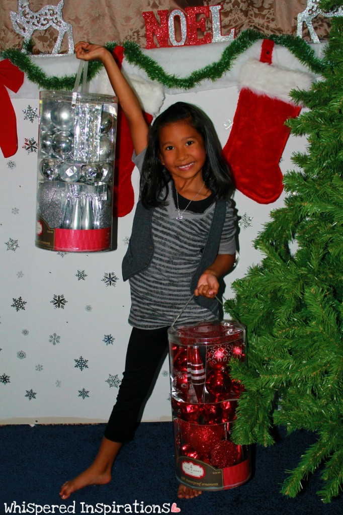 A little girl holds buckets of ornaments for the Christmas tree. 