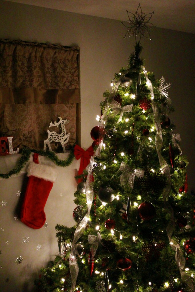 The Christmas tree fully trimmed and with decor surrounding it. 