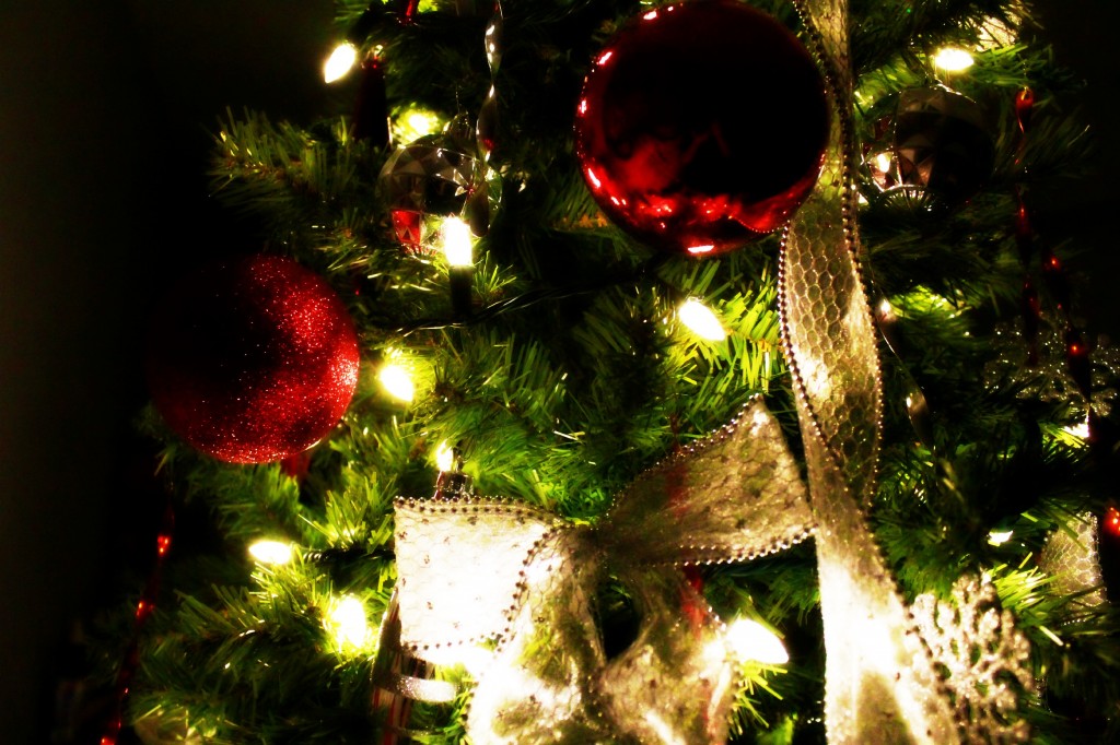 LED lights shine on a tree and reflect on Christmas ornaments.