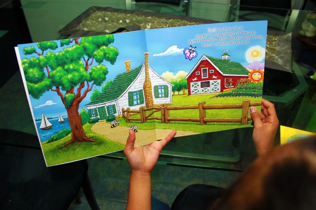 A little girl holds a book open. 