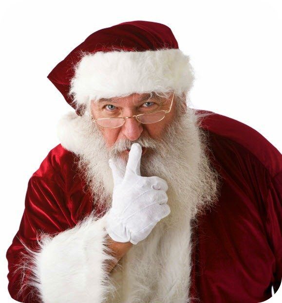 Santa Claus looking at you and putting his finger in a shh motion on his lips. 