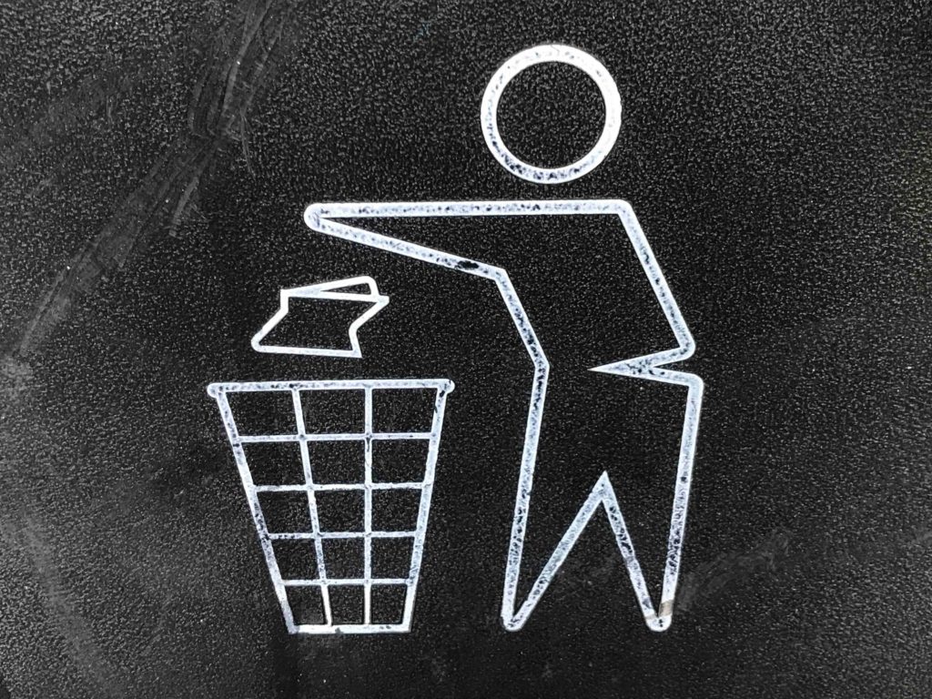 Sign showing a person placing garbage in trash bin. 