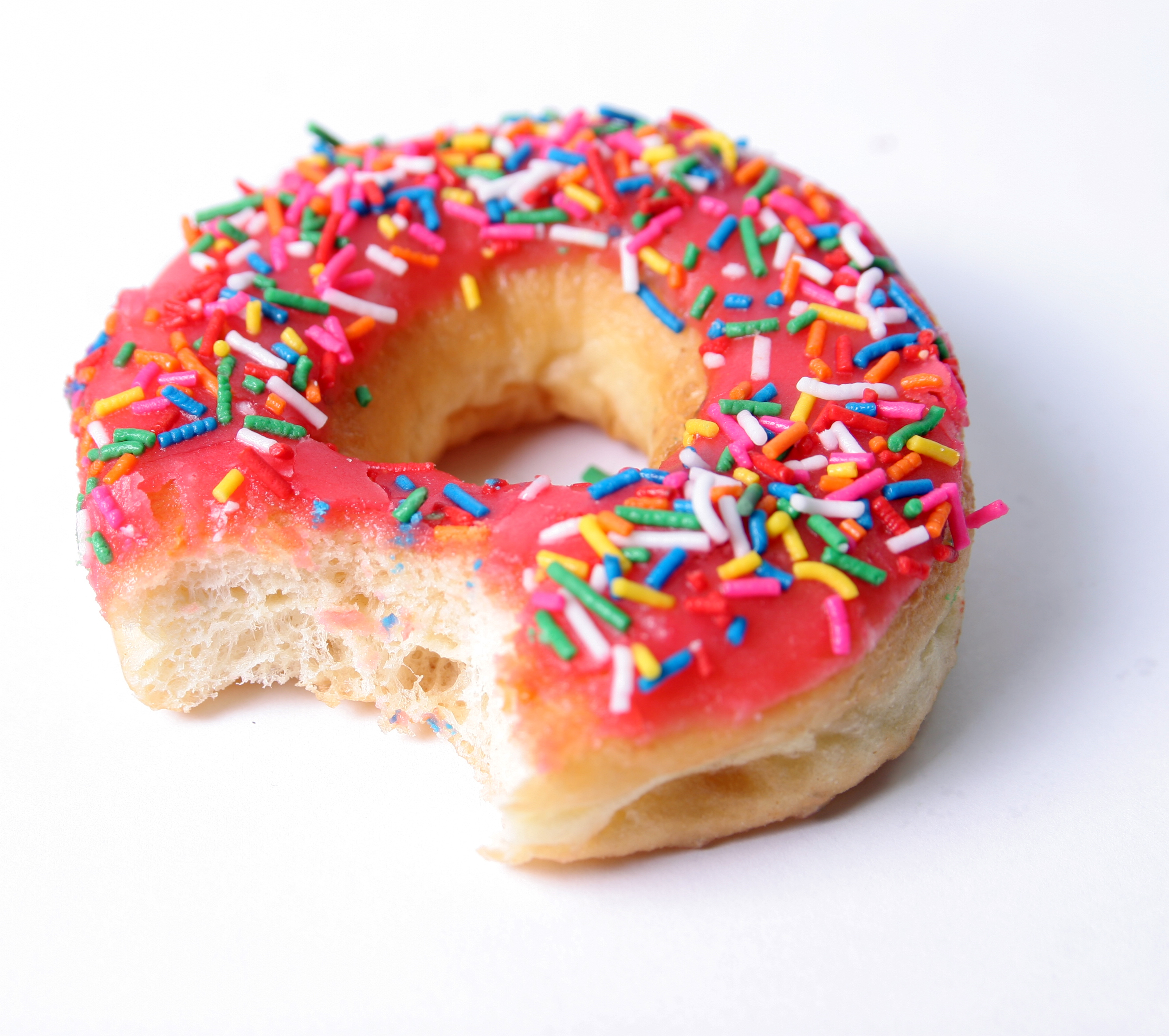 A pink sprinkle donut with a bite taken out. 