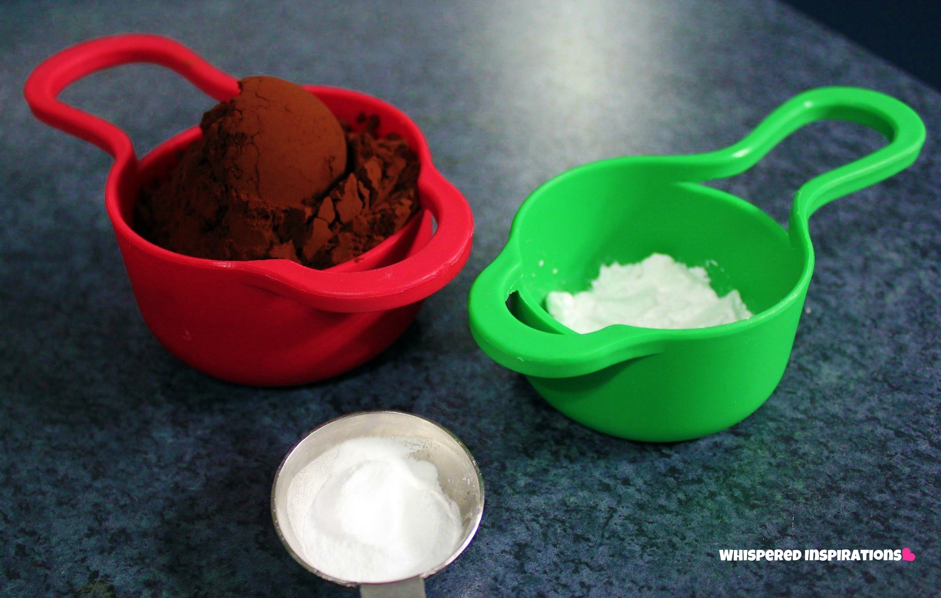 Measuring cups filled with baking soda, stevia, and cocoa powder.