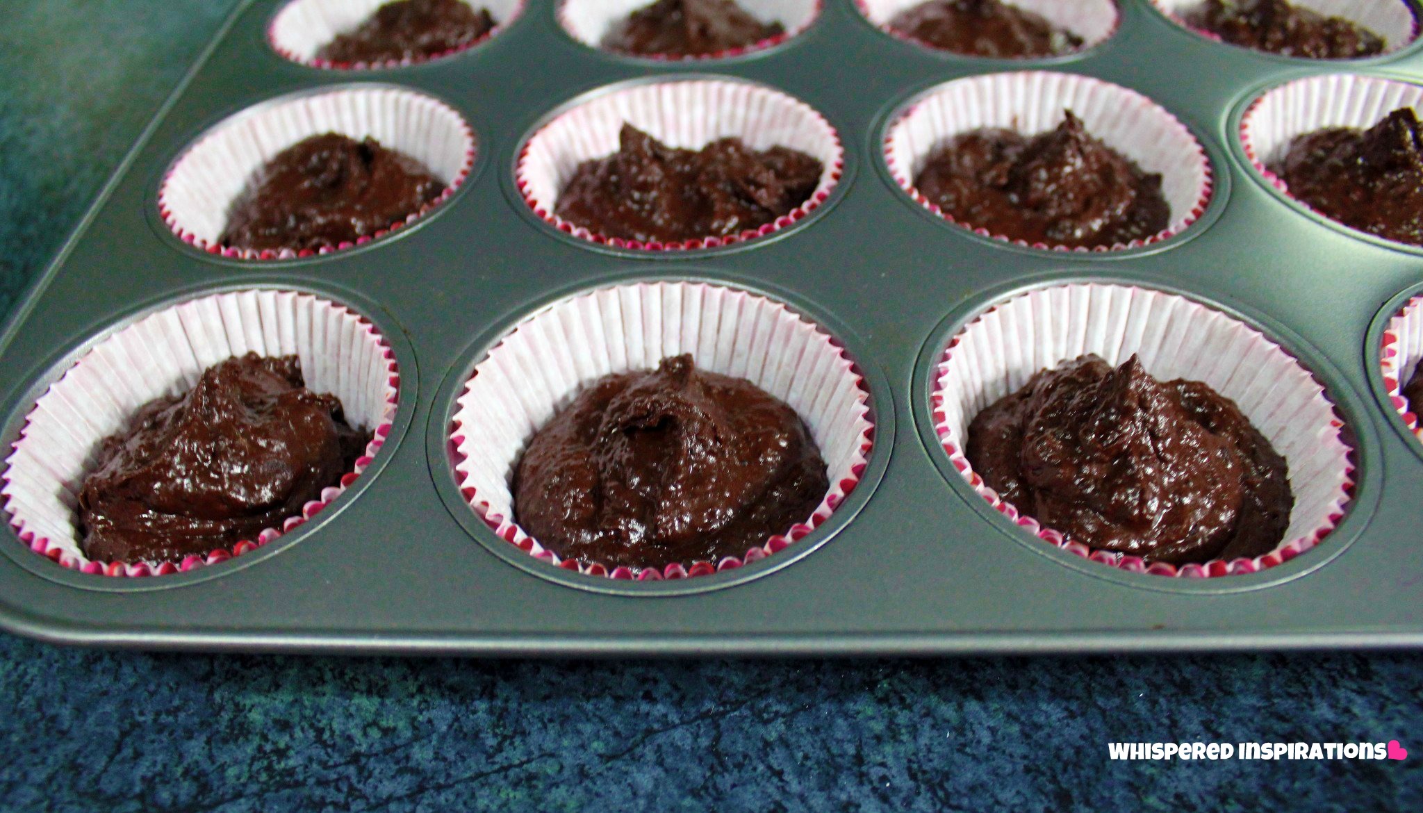 A close up of cupcake tin filled with chocolate batter.