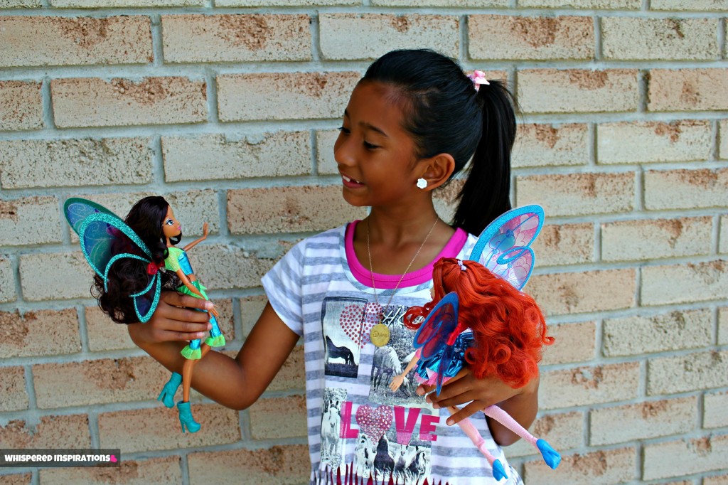 Gabby looking down at her two dolls and smiling. 