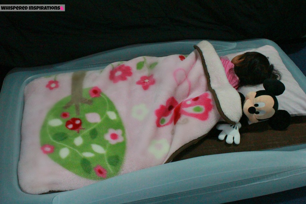 Mimi sleeping with Mickey plush in her indoor toddler travel bed.