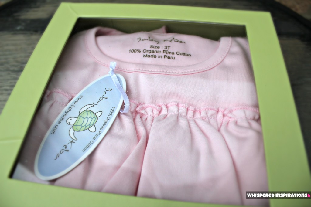 Top view of garment box with clear panel showing off the organic pink dress. 