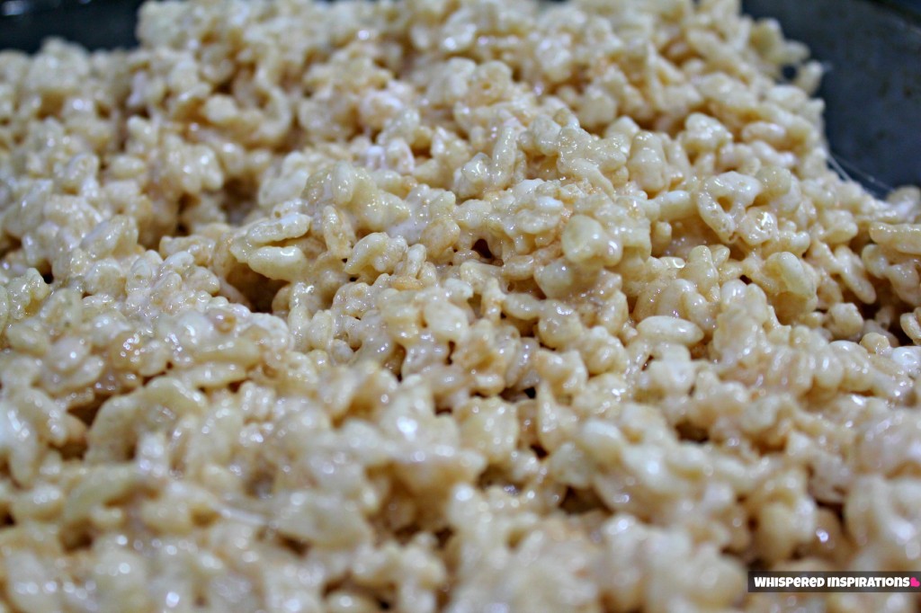 Rice Krispies all mixed up and ready to be placed in a pan.