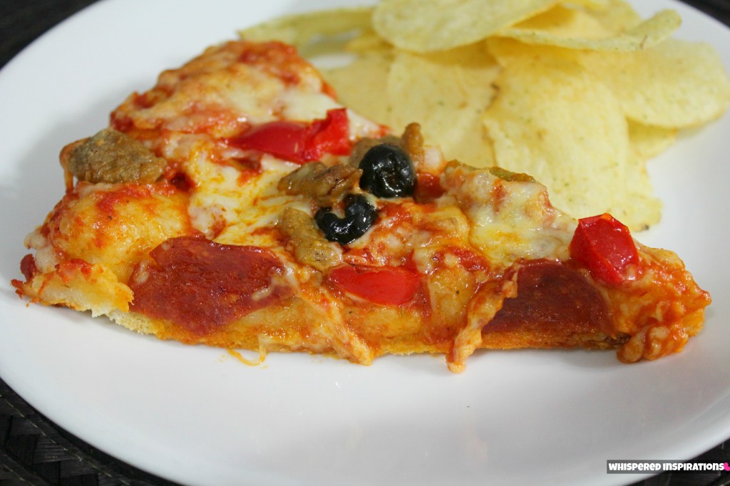 A slice of pizza and potato chips are shown on a plate. 