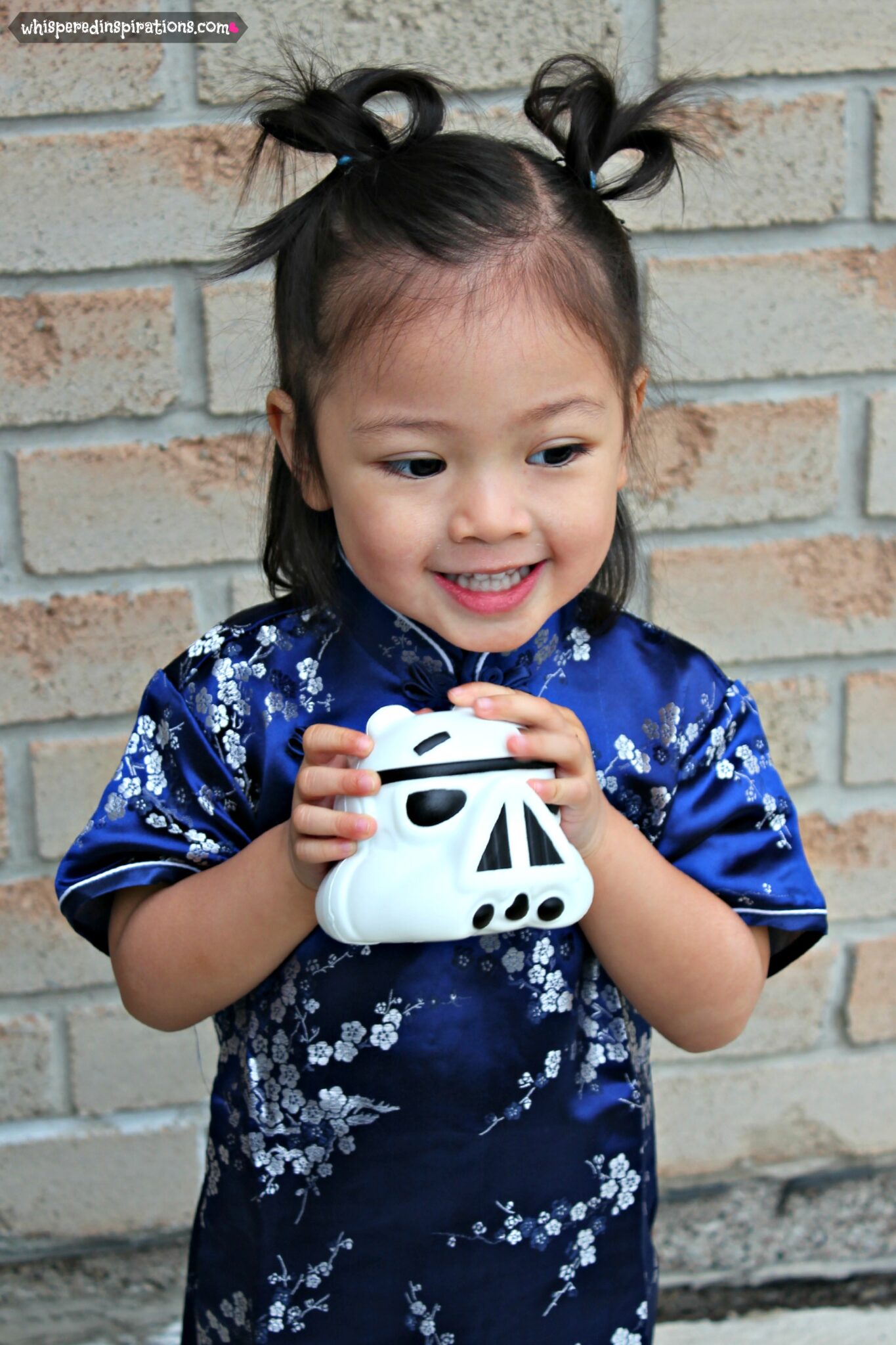 Mimi is dressed in a traditional Chinese dress while holding an Angry Birds toy.