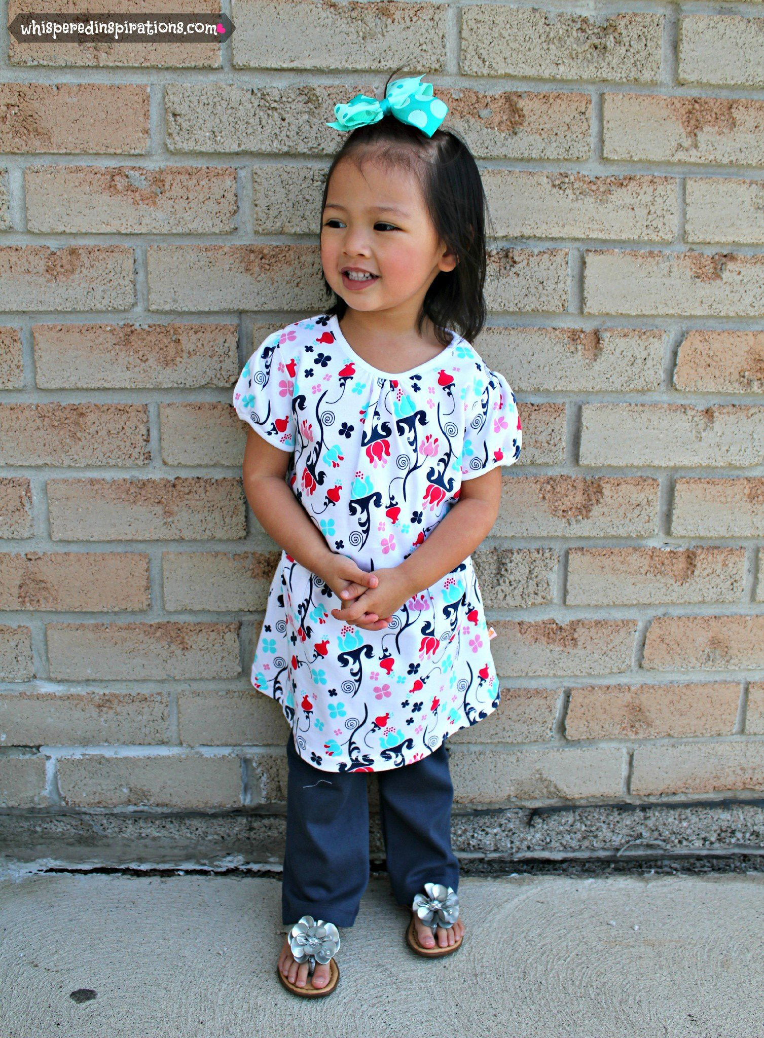 A cute little girl poses while wearing a shirt dress from Nosilla Organics.
