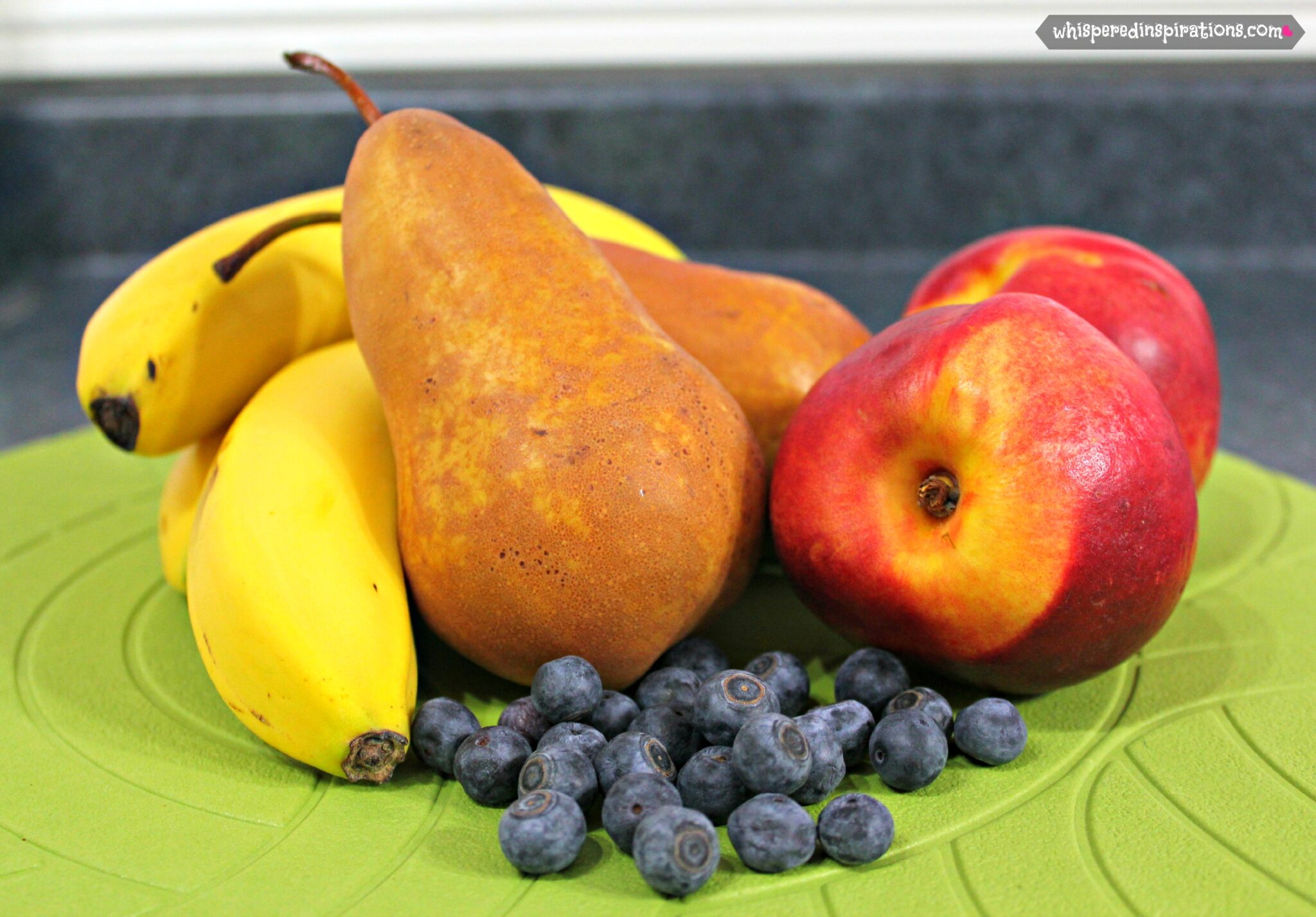 Bananas, pears, peaches, and blueberries are shown and ready to be made into puree.