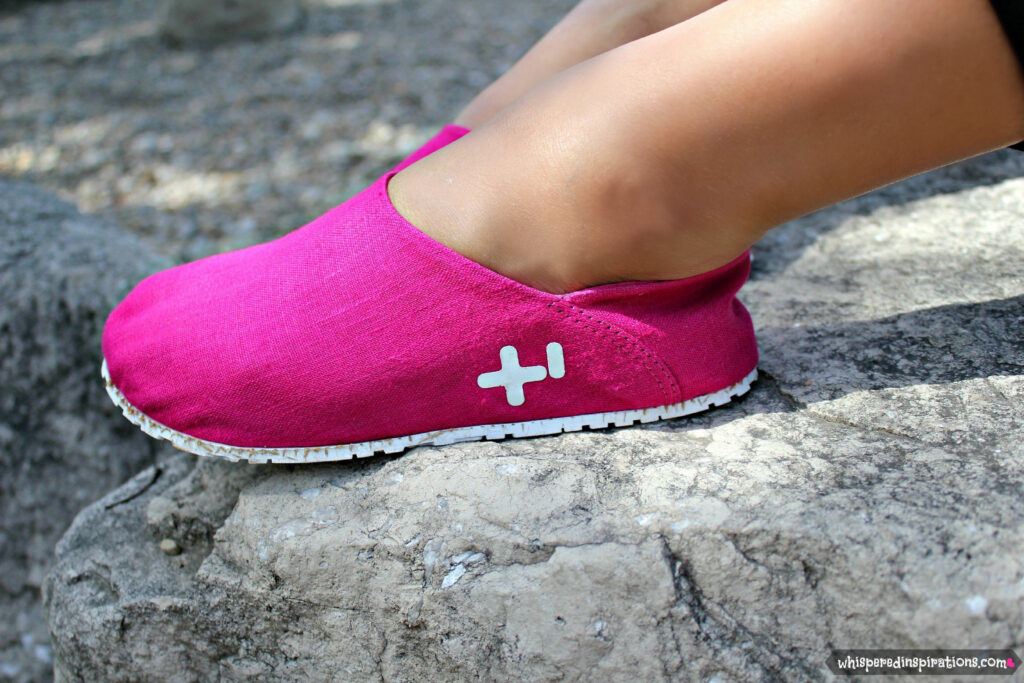 Nancy sits on a rock and a close up of the shoe is shown. 