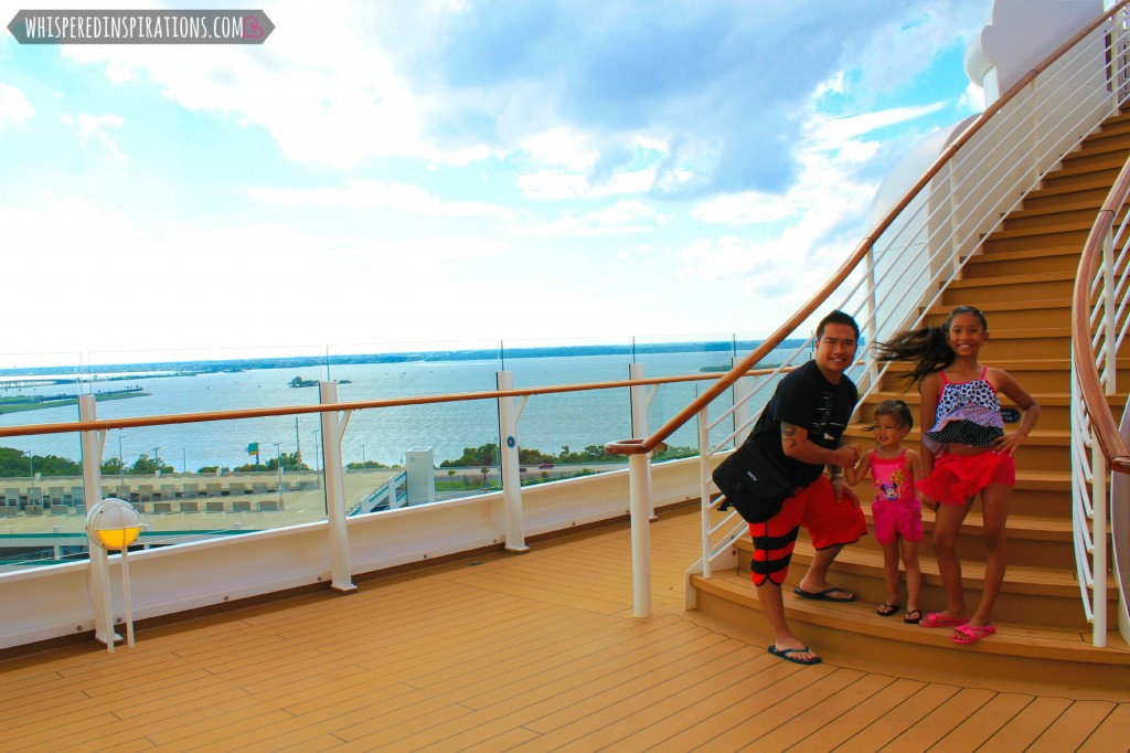 The girls stand on a staircase aboard the Disney Dream with their dad.