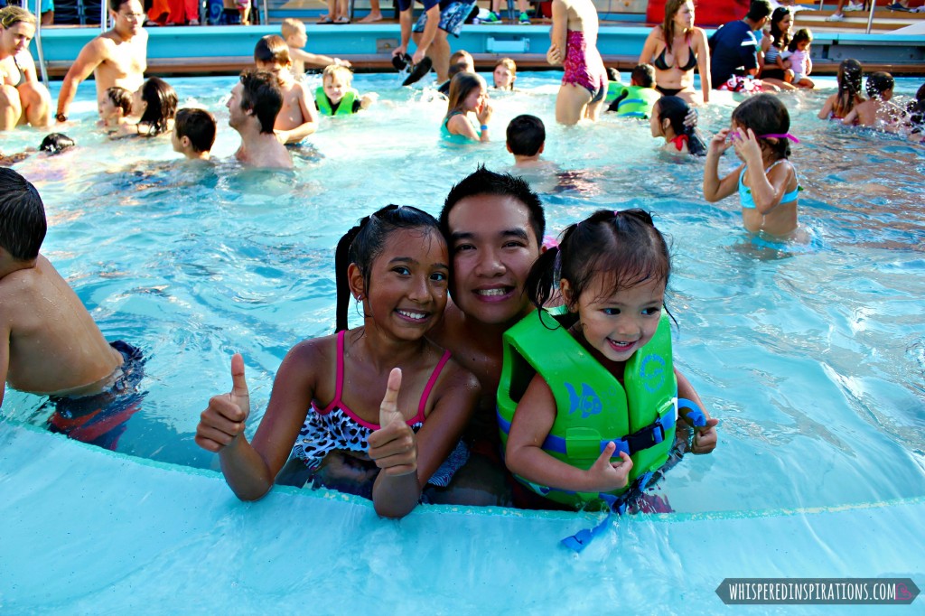 Two girls and her dad pose inside the pool on the Disney Dream. 