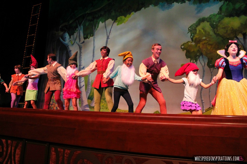 Kids dance with Snow White and dwarves on stage aboard the Disney Dream.