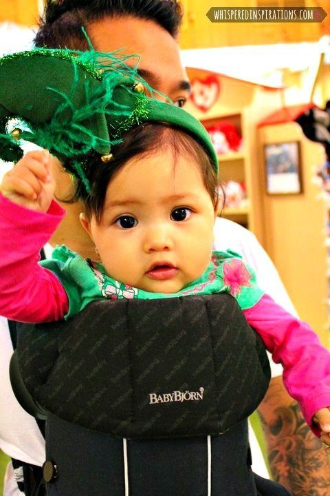 Little girl in a Baby Bjorn whilst wearing an elf headband. 