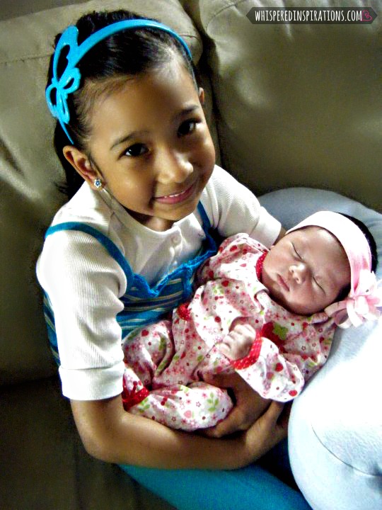 A little girl holds her infant sister. 