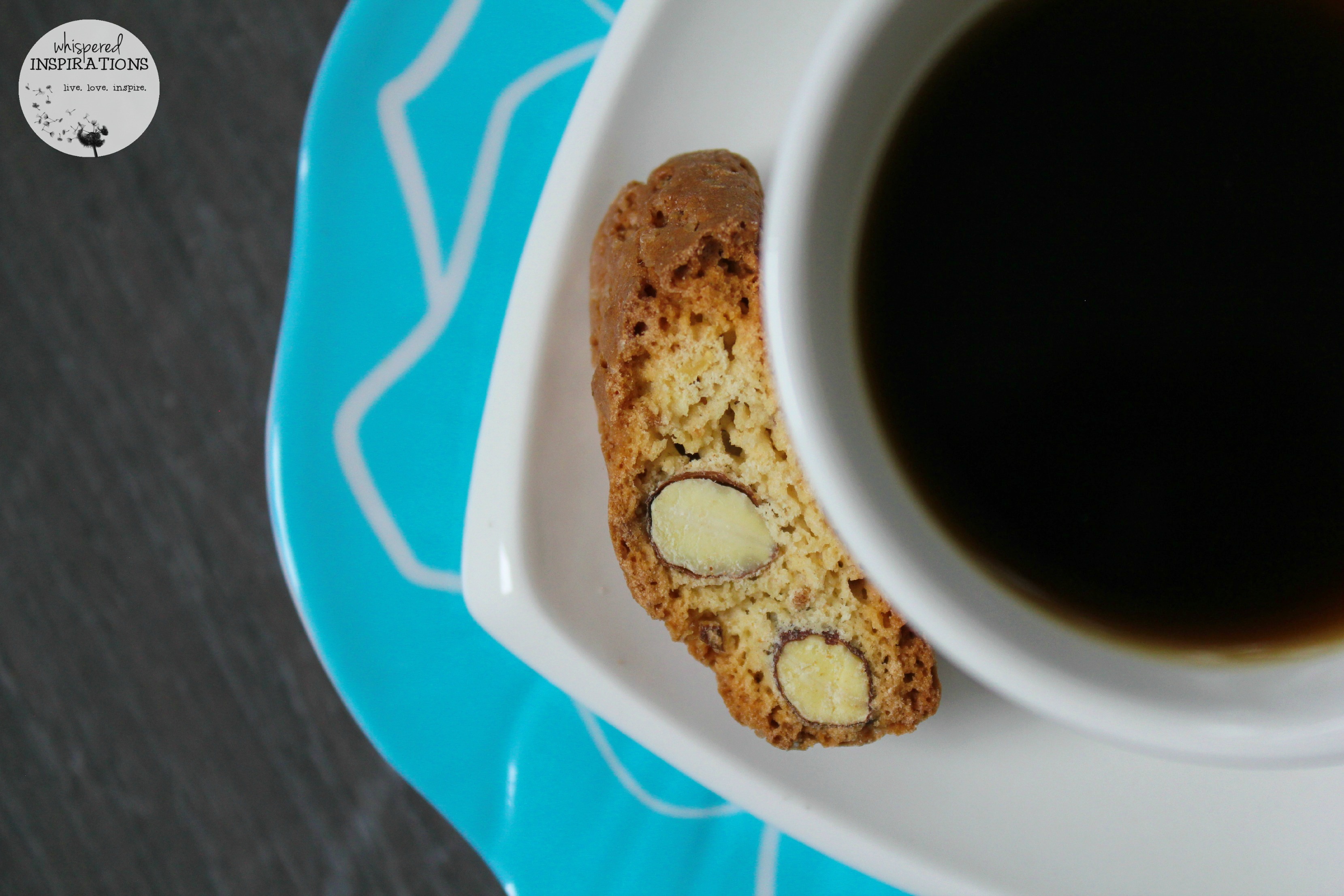 Close up of a biscotti with a black cup of coffee on two plates. 
