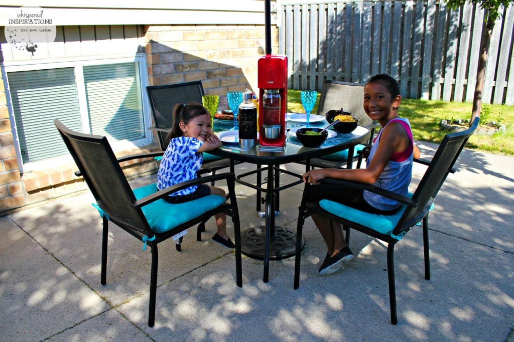 Two little girls await their BBQ meal while sipping on SodaStream sodas. 