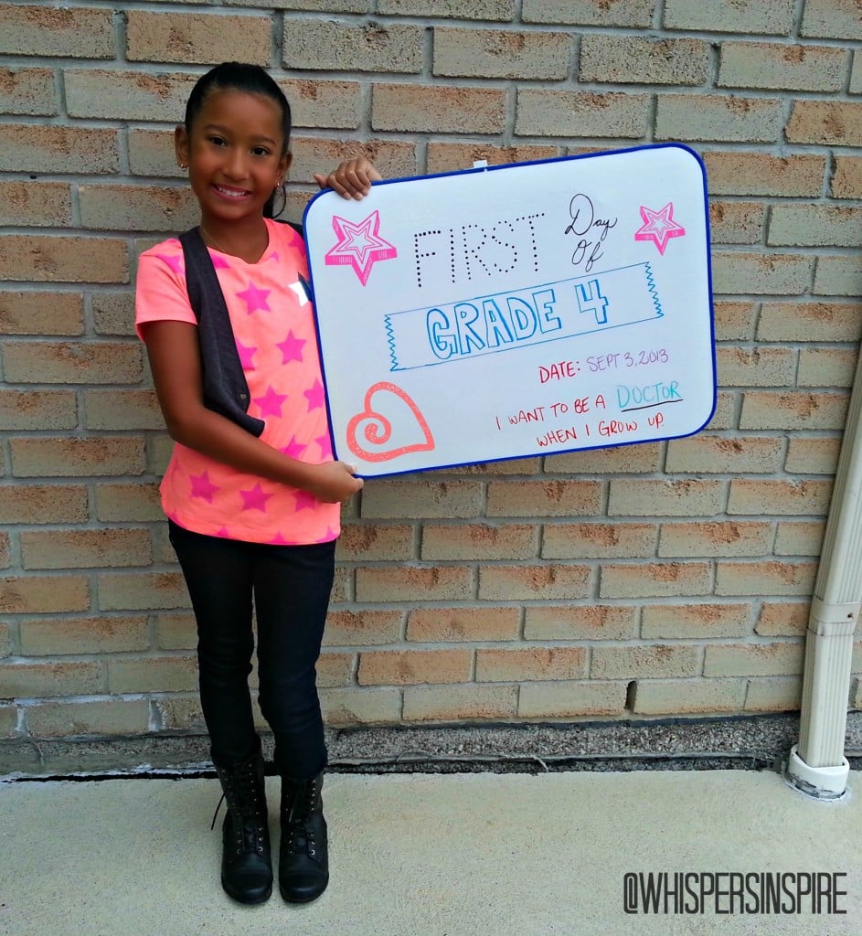 Little girl holds up board on first day of school. 