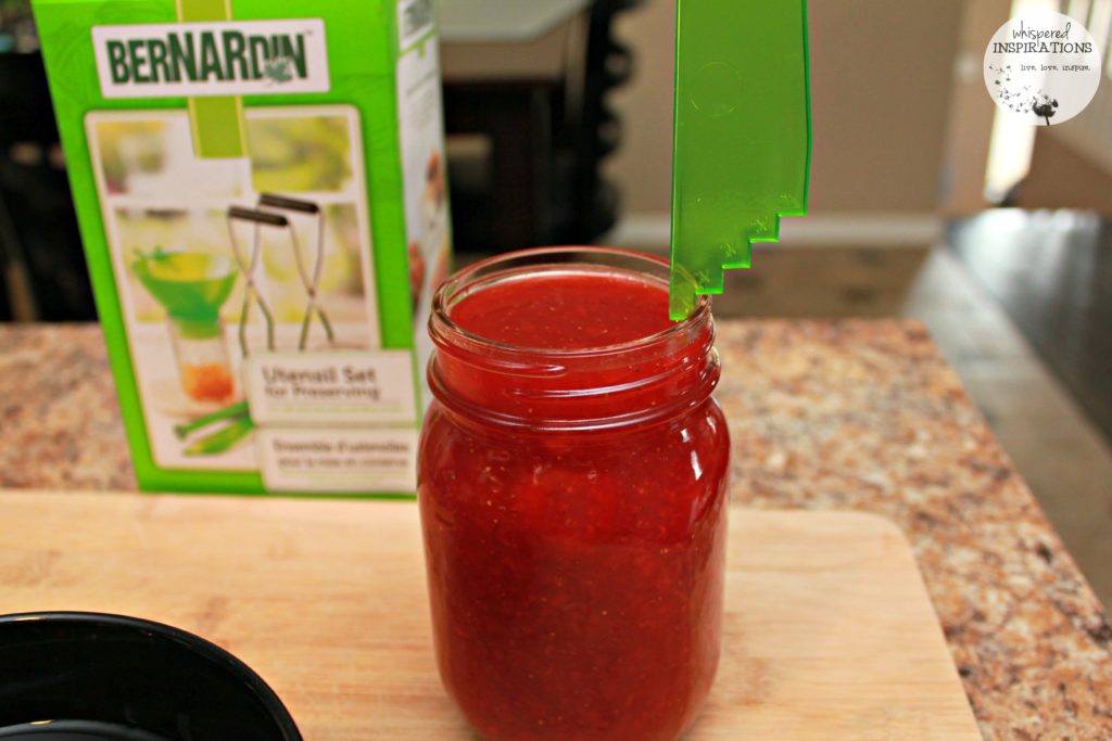 Using a Bernardin measuring tool to see how much to fill mason jars for jam. 