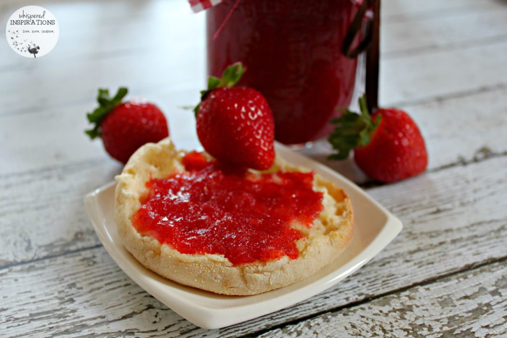 The organic strawberry jam spread on an English muffin.