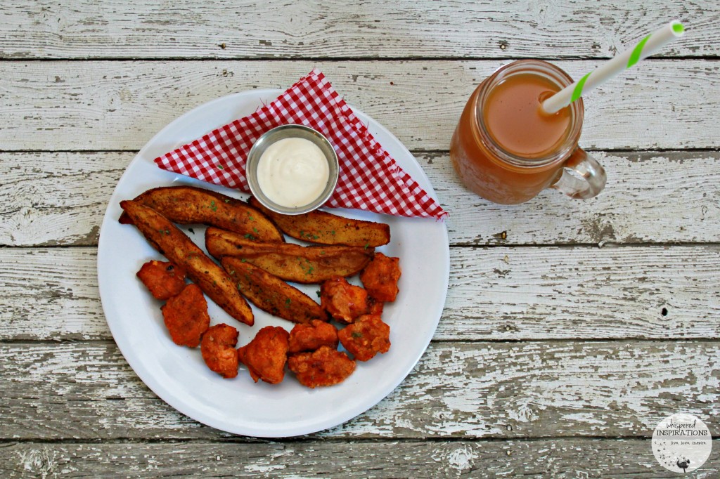 A top view of the finished meal of air fryer buffalo wings and air fryer potato wedges with a mason jar of apple cider. 