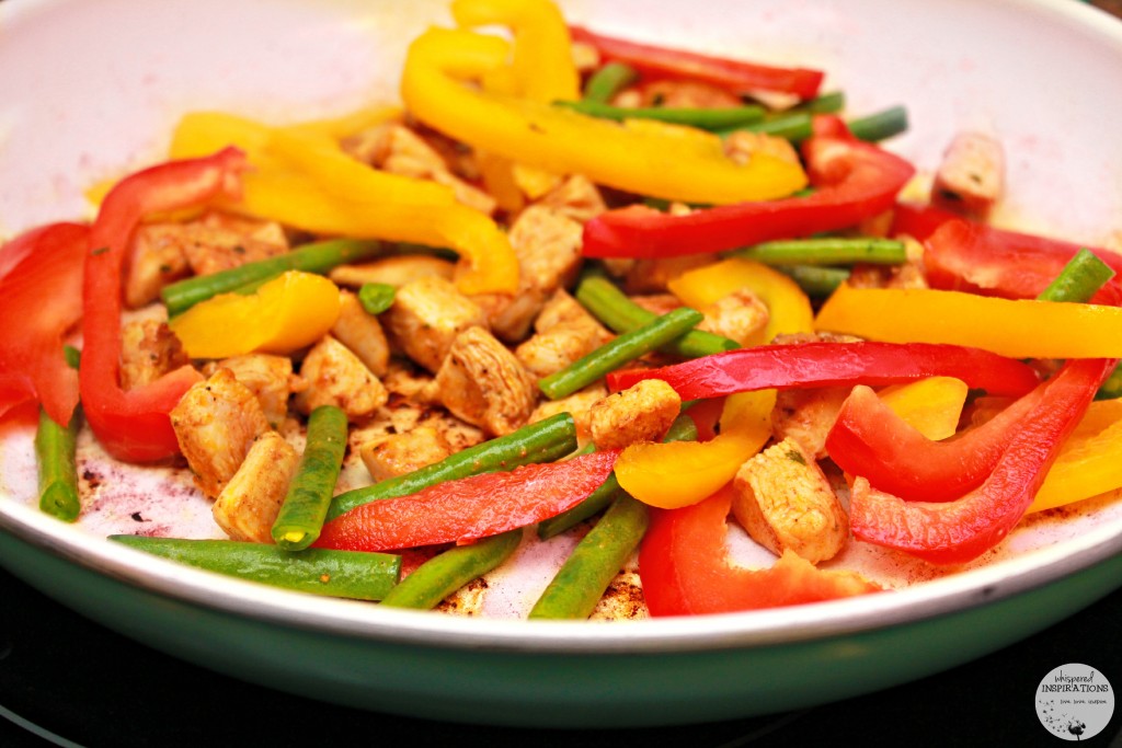 Skillet with red and yellow pepper, and green beans cook. 