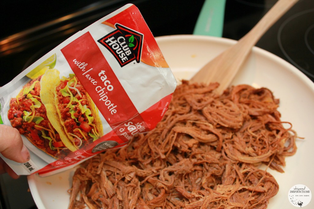 Taco with Chipotle being poured on top of shredded beef. 