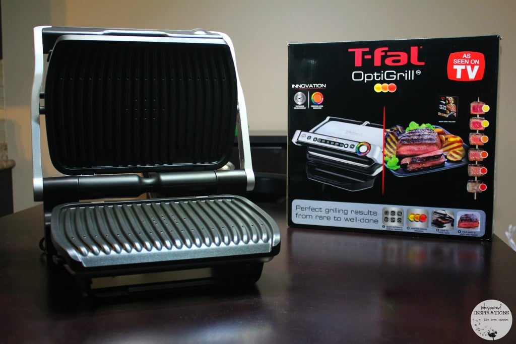 The T-fal Optigrill is displayed open on a kitchen table. 