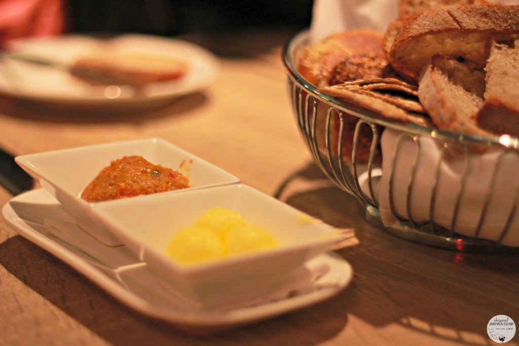 Flavored butter and a bread basket. 