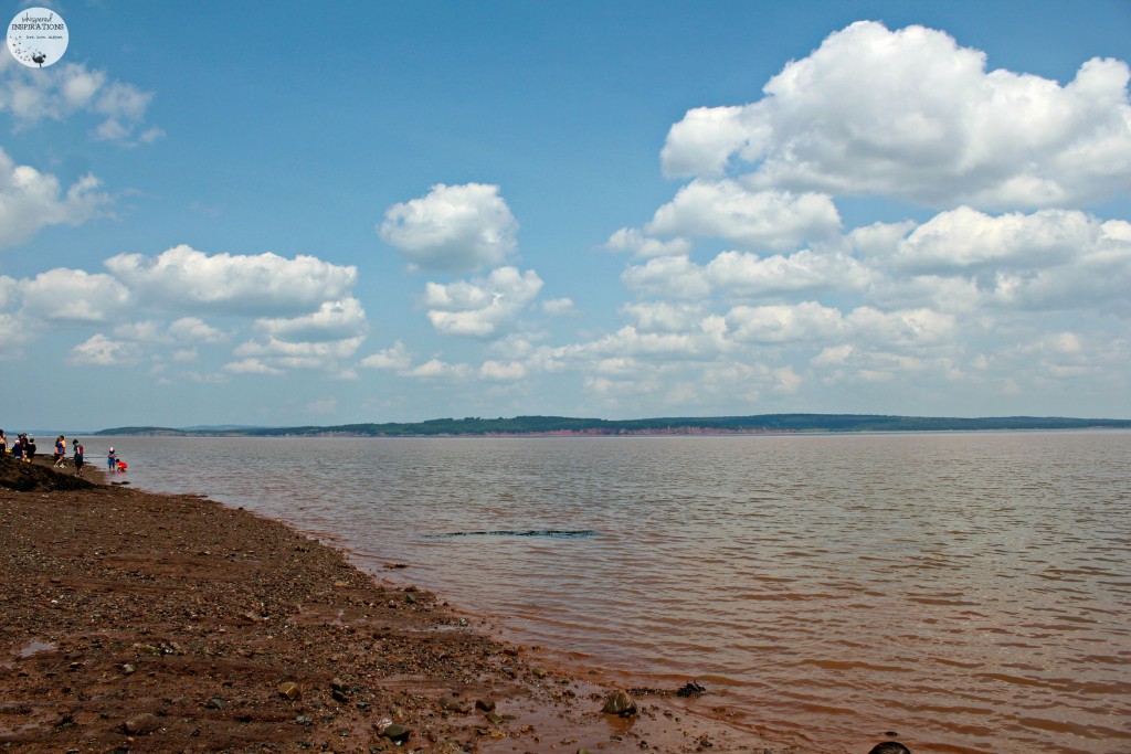 A beautiful sky is mirrored in the orangey-clay waters of the Bay of Fundy at low tide.