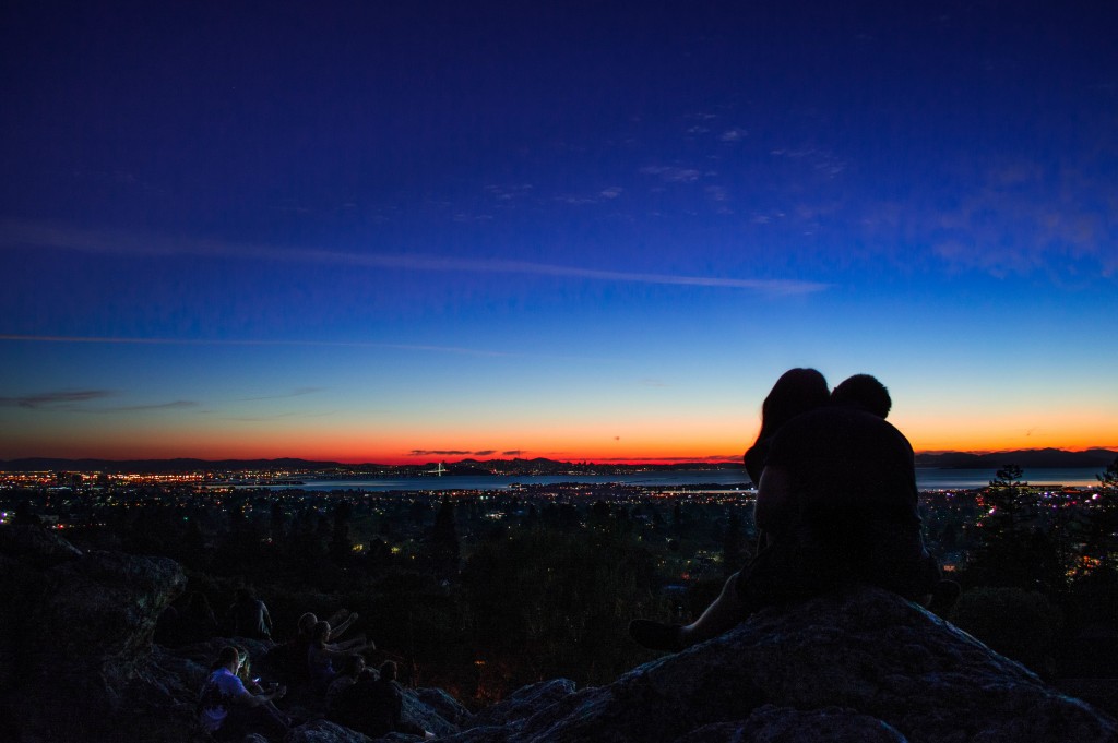 A couple embrace while they overlook the city at night. Keep the spark alive.