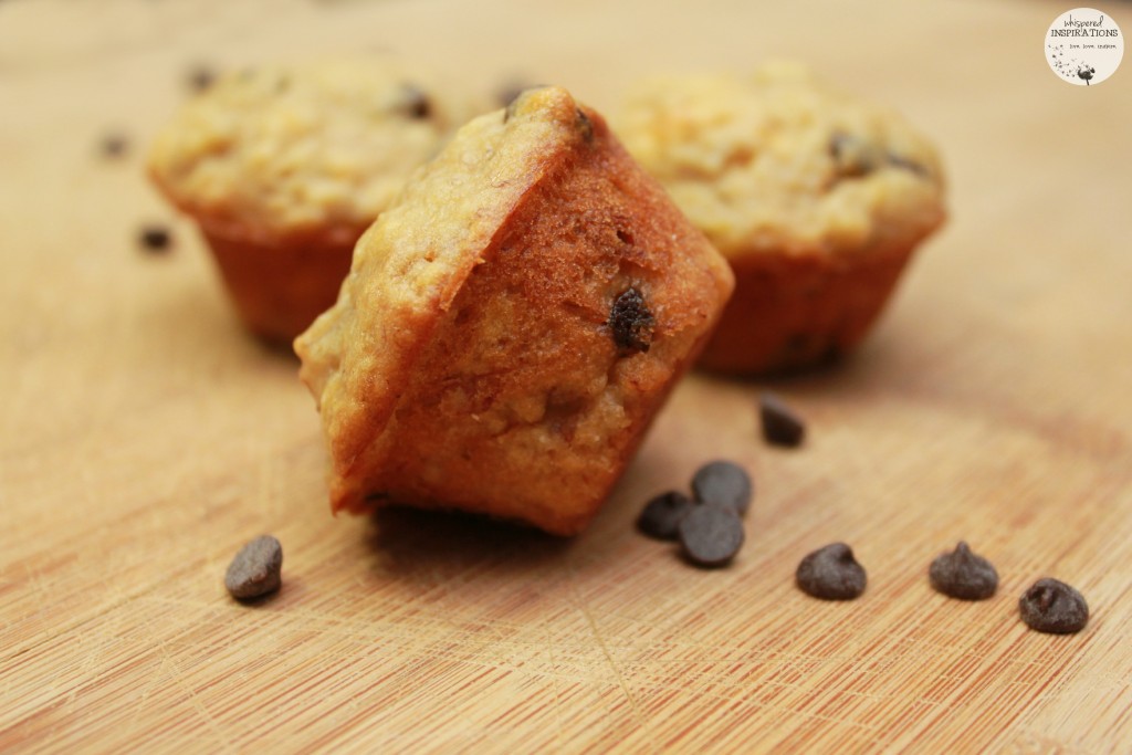 Perfect Mini Banana Chocolate Chip Muffins are on a wooden board surrounded by chocolate chips.