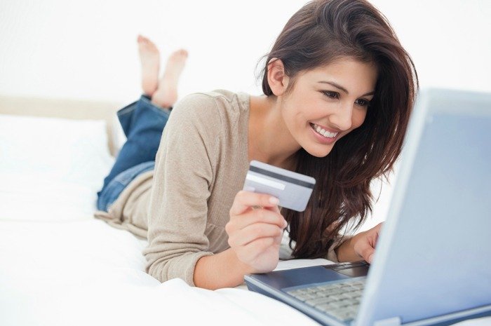Woman on her laptop with credit card in hand and smiling shopping on retailmenot.