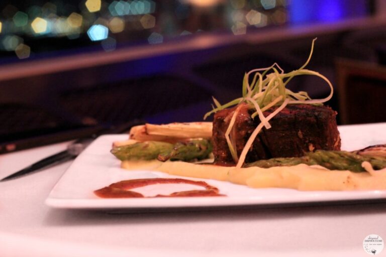 A piece of aged steak cooked to perfection is pictured, in the background you can see the Ambassador Bridge.