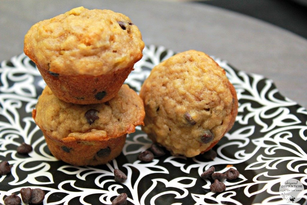 Mini banana chocolate chip muffins are stacked on a plate. 