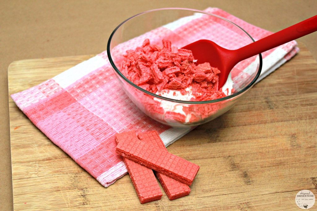 Strawberry Voortman cookies being crushed and mixed with cake icing. 