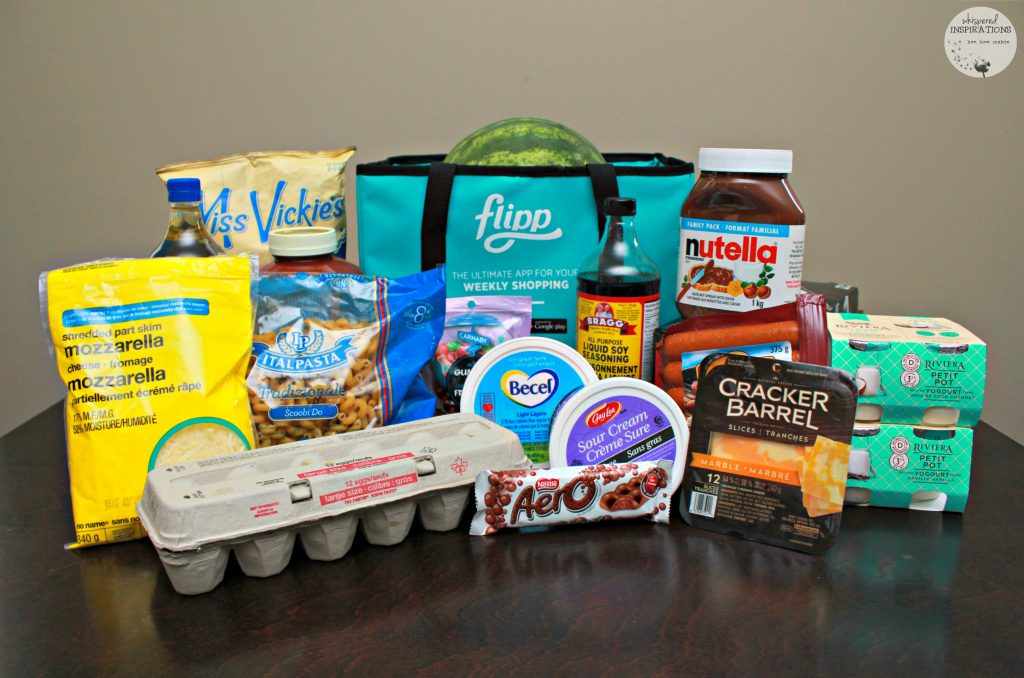 A kitchen table filled with groceries. Eggs, cheese, pasta, yogurt, watermelon, and more!