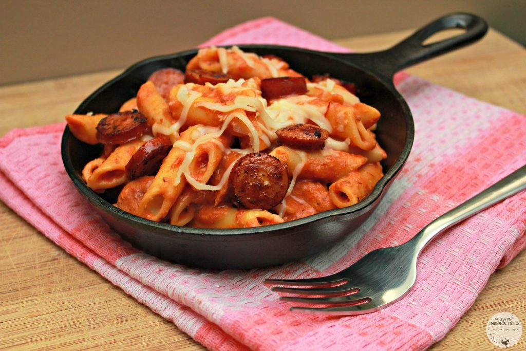 A skillet is filled with baked penne and sausage.