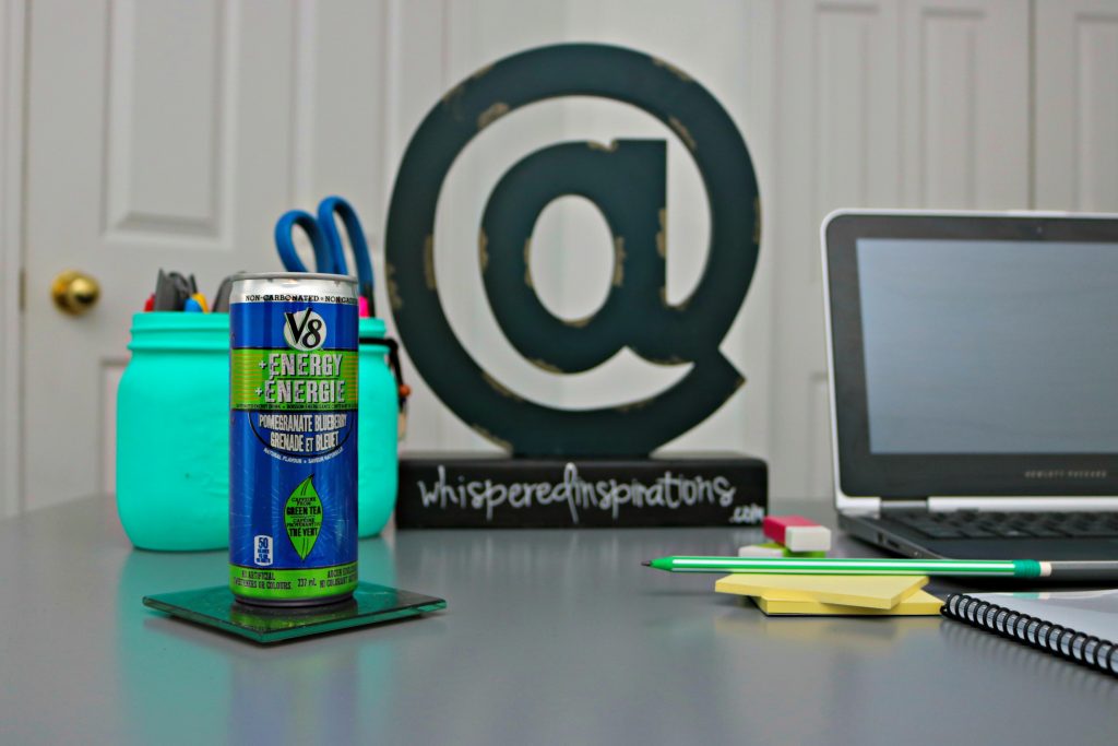 Desk with laptop, pens and pencils, and a V8 Energy drink. 
