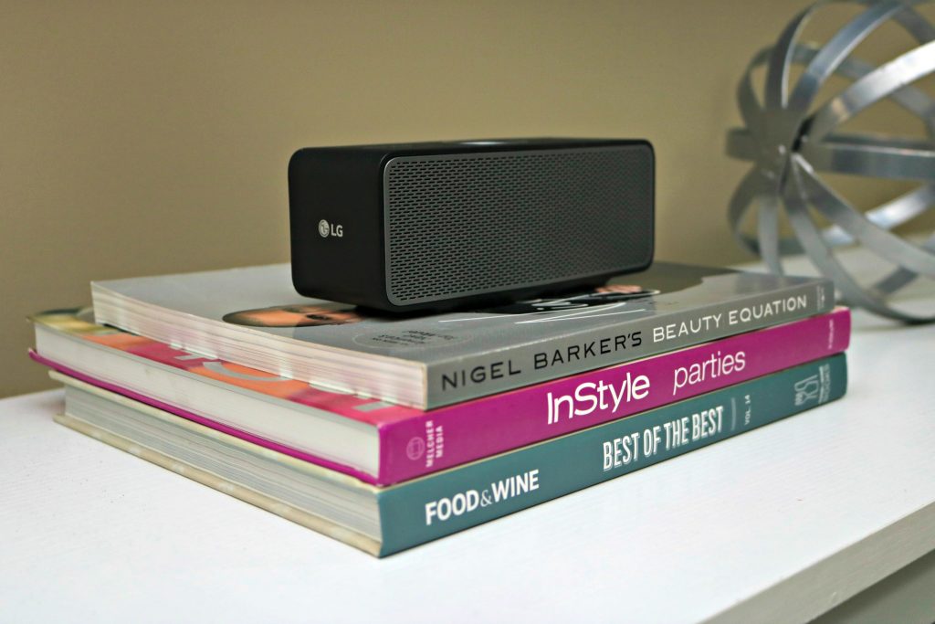 Another view of the LG speaker that is sitting on stack of books. 