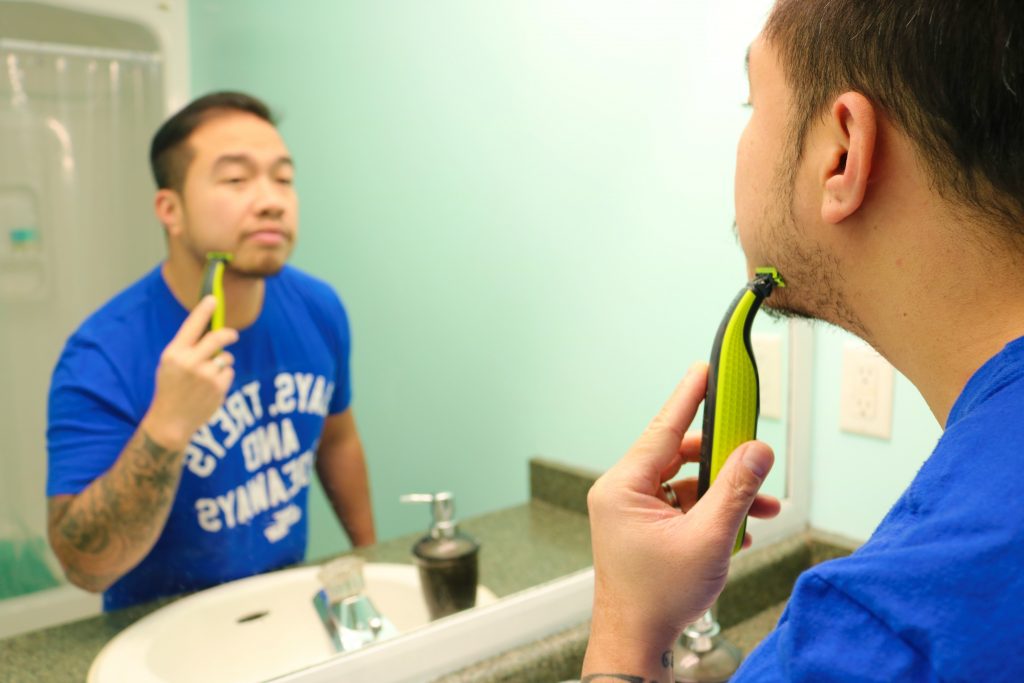 Darasak shaving his face in front of mirror. He is using the Philips One Blade.